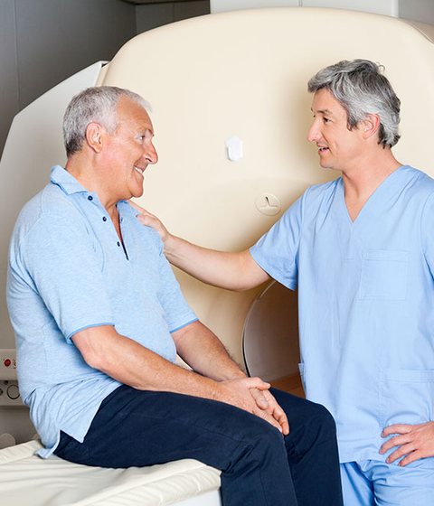 A friendly technician chatting with a relaxed patient beside a scanner